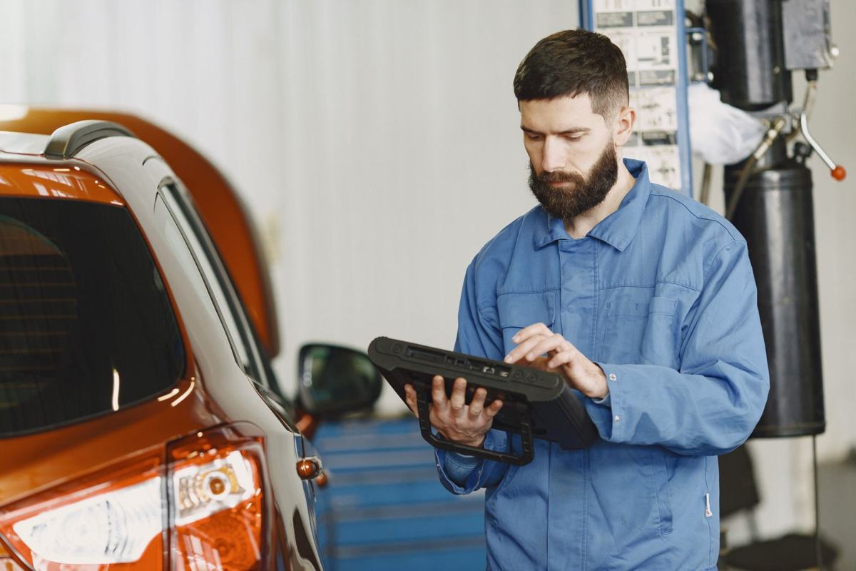 Mecânico consultando o sistema no tablet ao lado do carro
